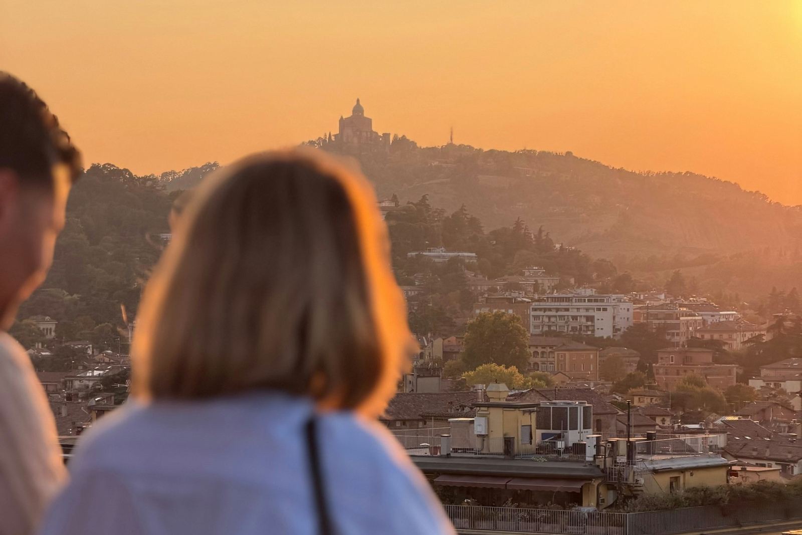 Una pareja mira la ciudad desde su balcón al atardecer. Imagen ilustrativa.