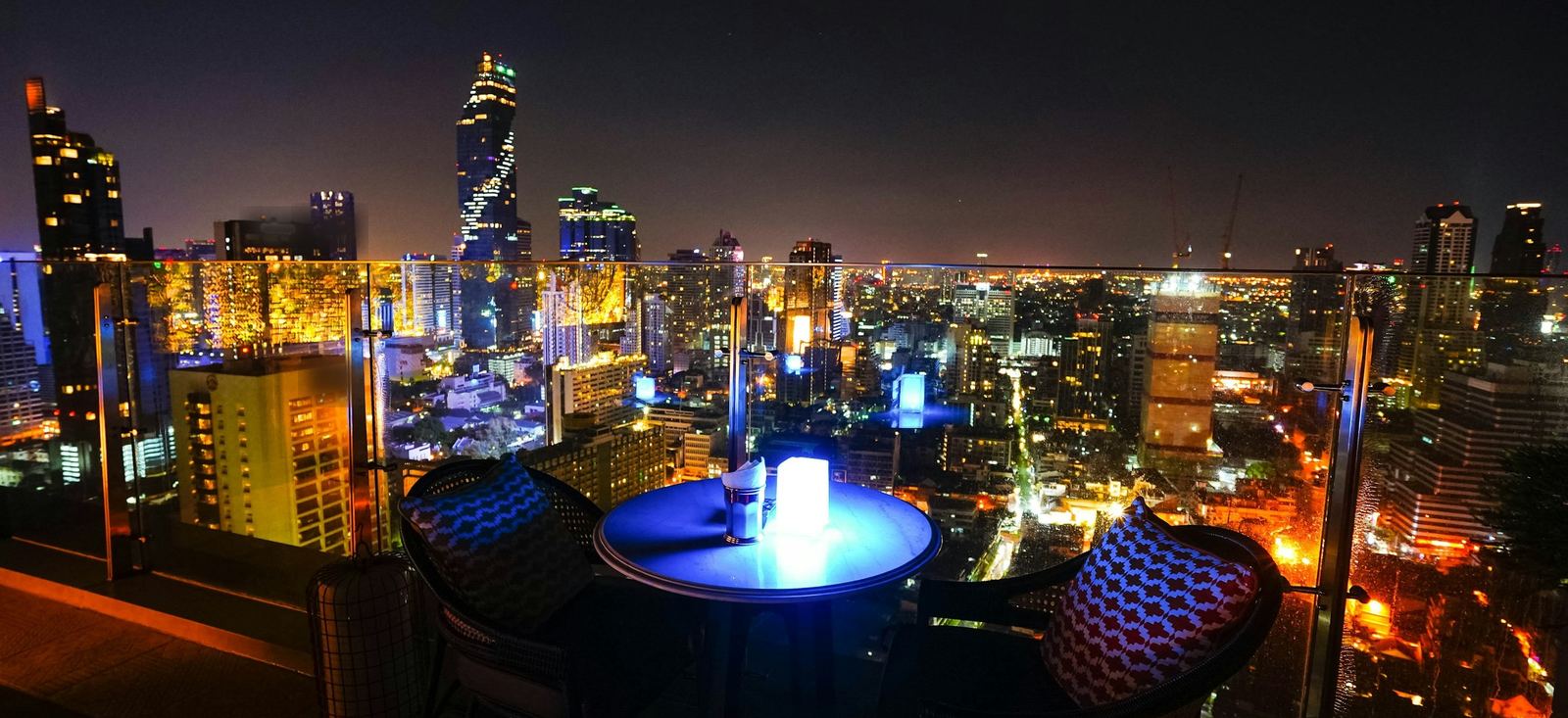 Terraza sobre la ciudad de noche, con la mesa puesta. Imagen ilustrativa.